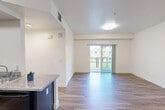 Located at 200 E Tenth St in Gilroy, CA, this single-floor residence offers four bedrooms and three bathrooms within a thoughtfully designed layout. The open-concept kitchen and living room serve as the heart of the home, featuring rich dark cabinetry, granite-style countertops, and black appliances including a refrigerator, range, and dishwasher — all set atop durable wood-style flooring. The living area is bright and airy, benefiting from natural light that pours in through sliding glass doors leading to a private balcony with views of the surrounding community grounds, including an outdoor recreation area.

The bedrooms are carpeted for comfort, with neutral tones and clean white walls creating a calm atmosphere. Each bedroom offers closet storage with built-in shelving, and windows provide additional natural light and outdoor views. The primary bedroom connects directly to a bathroom for added privacy.

The three bathrooms are well-appointed with granite-style vanity countertops, dark cabinetry, and wood-style flooring. Accessibility features are present throughout, including grab bars near the toilet and bathtub areas. One bathroom features a full tub-shower combination. The hallway and entry area maintain the same wood-style flooring, ensuring a cohesive and polished look throughout the entire residence.