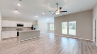 Located at 190 Treadstone Way in Fairhope, Alabama, this well-appointed single-story home offers four bedrooms, three bathrooms, and a thoughtfully designed open floor plan. The heart of the home is a bright, open-concept kitchen and living area highlighted by vaulted ceilings, recessed lighting, and a ceiling fan. Light-toned luxury vinyl plank flooring flows throughout the main living spaces, complementing the neutral wall tones that create a clean, modern aesthetic. The kitchen is equipped with white shaker cabinetry, granite countertops, stainless steel appliances including a French door refrigerator, and a central island with a sink — ideal for both cooking and casual entertaining. Large windows in the living area invite abundant natural light and views of the surrounding greenery. The spacious primary bedroom features plush carpeting and generous walk-in closet space with wire shelving systems. Additional bedrooms are well-sized with comfortable carpet flooring. The bathrooms are finished with clean, classic fixtures including a tub-shower combination. A dedicated laundry room accommodates a full-size washer and dryer. The attached garage offers ample space for vehicles and additional storage, completing this functional and comfortable home.