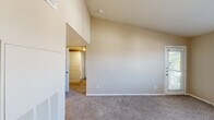 This single-story, 2-bedroom, 2-bathroom home offers a thoughtfully arranged layout designed for comfortable everyday living. The living area immediately impresses with striking vaulted ceilings that amplify the sense of space, neutral beige walls, and soft wall-to-wall carpeting underfoot. A glass-panel exterior door and adjacent window allow natural light to fill the room, creating a bright, welcoming ambiance.

The kitchen is well-equipped with rich dark wood cabinetry, light quartz countertops, stainless steel appliances including a range and refrigerator, and a clean white subway tile backsplash that adds a modern touch. Light wood-style flooring grounds the space practically and stylishly.

The primary bedroom is generously sized, featuring dual windows with blinds that invite natural light and outdoor views, a ceiling fan with light fixture, and plush carpeting. The second bedroom similarly offers carpeted floors, a window with blinds, and a ceiling fan, making it a comfortable and versatile space.

Both bathrooms are finished with dark wood vanity cabinetry, light quartz countertops, large framed mirrors, brushed nickel fixtures, and tub-shower combinations with clean white surrounds. A connecting hallway links the bedrooms and bathrooms efficiently, and two closets provide ample storage throughout the home.