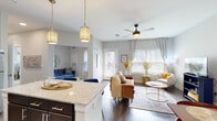 This single-story residence in Buford, Georgia offers a thoughtfully designed open-concept floor plan that seamlessly connects the kitchen, dining, and living areas. The kitchen is outfitted with dark espresso cabinetry, light granite countertops, a classic subway tile backsplash, and a full suite of stainless steel appliances, including a refrigerator, range, microwave, and dishwasher. A kitchen island with pendant lighting provides additional prep space and serves as a natural divider between the kitchen and the main living area. The living room is bright and welcoming, with large windows dressed in plantation shutters and sheer draping curtains that allow abundant natural light to fill the room. Wood-style flooring runs throughout the main living spaces, adding warmth and continuity. The dining area offers a dedicated nook with ample room for a full dining set, complemented by neutral walls that create an understated, elegant backdrop. The bedroom is a serene retreat featuring plush carpeting, a ceiling fan, and a stylish barn-style sliding door leading to a spacious walk-in closet with built-in shelving and hanging storage. The overall ambiance throughout the residence is modern and refined, with a cohesive neutral palette accented by contemporary fixtures and finishes.