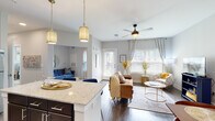 This single-story residence in Buford, Georgia offers a thoughtfully designed open-concept floor plan that seamlessly connects the kitchen, dining, and living areas. The kitchen is outfitted with dark espresso cabinetry, light granite countertops, a classic subway tile backsplash, and a full suite of stainless steel appliances, including a refrigerator, range, microwave, and dishwasher. A kitchen island with pendant lighting provides additional prep space and serves as a natural divider between the kitchen and the main living area. The living room is bright and welcoming, with large windows dressed in plantation shutters and sheer draping curtains that allow abundant natural light to fill the room. Wood-style flooring runs throughout the main living spaces, adding warmth and continuity. The dining area offers a dedicated nook with ample room for a full dining set, complemented by neutral walls that create an understated, elegant backdrop. The bedroom is a serene retreat featuring plush carpeting, a ceiling fan, and a stylish barn-style sliding door leading to a spacious walk-in closet with built-in shelving and hanging storage. The overall ambiance throughout the residence is modern and refined, with a cohesive neutral palette accented by contemporary fixtures and finishes.