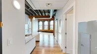 Located in the heart of Syracuse, NY, this one-bedroom, one-bathroom loft-style unit masterfully blends industrial character with contemporary updates. The open layout flows from the kitchen through the living area, all unified by warm hardwood flooring and soaring ceilings with exposed wooden beams and visible ductwork that pay homage to the building's historic origins.

The kitchen is well-appointed with white shaker cabinetry, granite countertops, a peninsula island with an undermount sink, and a full suite of stainless steel appliances, including a refrigerator, electric range, and microwave. Pendant lighting adds a modern touch overhead.

The living area is the architectural highlight of the space, anchored by a row of grand arched windows framed in original exposed brick. These striking windows flood the room with natural light and offer sweeping elevated views of downtown Syracuse and the surrounding cityscape.

The bathroom features neutral tile flooring, a granite-topped vanity with white cabinetry, and clean, modern fixtures. Additional storage is provided by two closets, and a hallway connects the private bedroom to the main living spaces. The overall ambiance is an inviting mix of historic industrial charm and polished, move-in-ready modern design.