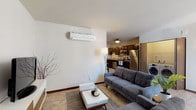 This single-floor residence offers a well-organized layout designed for comfortable everyday living. The living area is generously proportioned, featuring neutral walls, stone-look tile flooring, and a wall-mounted mini-split climate control unit. Natural light filters in through large windows, and the open flow connects seamlessly to the kitchen and a dedicated laundry area housing a side-by-side washer and dryer.

The kitchen is outfitted with rich, dark-stained cabinetry extending to the ceiling for ample storage, light-toned countertops, a double-basin sink, and a full suite of stainless steel appliances including a refrigerator, dishwasher, microwave, and range. The stone-look tile flooring continues throughout.

The bedroom is carpeted and benefits from multiple large windows that frame views of surrounding urban architecture, filling the room with natural light. Two bathrooms serve the unit — one featuring a tub-shower combination with a dark vanity and stone-look tile flooring, and another similarly appointed with a walk-in shower configuration. Dark wood trim and consistent finishes tie the entire space together cohesively.