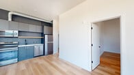 Located in Portland's vibrant Pearl District-adjacent neighborhood on NW Northrup Street, this contemporary single-floor unit offers a thoughtfully designed layout across a well-proportioned footprint. Light hardwood flooring flows throughout, complementing the clean white walls and modern aesthetic found in every room.

The open-concept living area is a standout feature, anchored by floor-to-ceiling windows that frame sweeping views of the Portland skyline, tree-lined streets, and the West Hills beyond, flooding the space with abundant natural light.

The kitchen is outfitted with stainless steel appliances—including a refrigerator, range, dishwasher, and over-the-range microwave—paired with sleek slate-blue cabinetry, a natural wood open shelf, white countertops, and a matte black faucet, delivering a polished, modern aesthetic with exposed ductwork accents.

The bedrooms are bright and well-sized, each benefiting from large windows with city and neighborhood views. The full bathroom features white subway tile surrounding the tub/shower, matte black fixtures, a warm wood vanity with gold hardware accents, white countertops, and an illuminated mirror. In-unit stacked laundry adds everyday convenience. Clean lines and a neutral palette give the entire unit a cohesive, contemporary character.