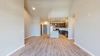 This single-floor residence showcases a thoughtfully designed open-concept layout that seamlessly connects the kitchen, dining, and living areas. The soaring vaulted ceilings in the main living space create an airy, expansive atmosphere, enhanced by pendant lighting and light-toned luxury vinyl plank flooring that flows throughout the common areas.

The kitchen is a standout feature, equipped with stainless steel appliances including a refrigerator, range, and microwave. Rich dark cabinetry is paired with granite countertops and a classic white subway tile backsplash. A central island with matching granite provides additional prep and dining space. Natural light enters the living area through a sliding glass door fitted with vertical blinds, offering outdoor access.

The bedrooms are carpeted for comfort and include ample natural light from windows. The primary bathroom features a walk-in glass shower, a granite-topped double vanity with dark cabinetry, and light vinyl flooring. A secondary bathroom offers a tub-shower combination and a matching granite vanity. Additional storage is provided by a walk-in closet outfitted with wire shelving. The overall palette of neutral tones and modern finishes gives the space a clean, contemporary character.