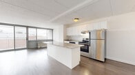 Located at 1350 15th St in Fort Lee, NJ, this 2-bedroom, 2-bathroom residence offers a well-designed, single-floor layout that balances functionality with modern finishes. The open-concept kitchen and living area forms the heart of the home, anchored by a large center island topped with granite countertops. White shaker-style cabinetry lines the kitchen walls, complemented by stainless steel appliances including a refrigerator, range, and dishwasher. Rich hardwood flooring runs throughout the main living areas, adding warmth to the bright, neutral palette. The spacious living room features floor-to-ceiling sliding glass doors that open to a balcony, filling the space with natural light and providing outdoor views. The generously sized primary bedroom offers ample room for comfortable furnishings, with hardwood floors continuing throughout. Both bathrooms are finished with clean, light tile work — one featuring a soaking tub with tiled surround, and the other a glass-enclosed walk-in shower — each appointed with modern wood-toned vanities and white countertops. The second bedroom is well-proportioned with bright white walls and hardwood floors. The overall ambiance is clean, modern, and move-in ready.