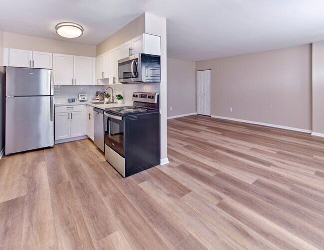 Cocina contemporánea con electrodomésticos de acero inoxidable y espacio de estar abierto en Village Square. - Village Square