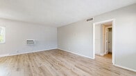 Located at 1311 N Azusa Ave in Azusa, California, this one-bedroom, two-bathroom residence offers a thoughtfully organized single-floor layout with a clean, modern aesthetic throughout. Light wood-style flooring runs continuously across all living areas, lending warmth and visual continuity to the space.

The open living area is generously proportioned, featuring neutral gray walls, a ceiling fan, a wall-mounted air conditioning unit, and windows that allow natural light to fill the room. The space flows naturally toward the kitchen, which is laid out in a galley configuration and equipped with stainless steel appliances — including a gas range and full-size refrigerator — white cabinetry, dark countertops, and an overhead ventilation hood.

The bedroom is a comfortable, well-lit room with a ceiling fan, a window overlooking the outdoors, and a sliding closet for storage. Two full bathrooms serve the unit; one features a tiled shower-over-tub combination with chrome fixtures and white subway-style tile surround. A hallway connects the main living areas to the private spaces, providing a clear and functional flow. The overall design is clean and neutral, offering a versatile canvas suited to a variety of living arrangements.
