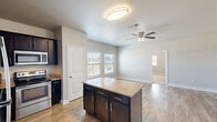 Located at 704 Dale Ln in White Settlement, TX, this single-story, one-bedroom, one-bathroom home offers a well-organized and functional layout across a compact yet efficient floor plan. The open-concept kitchen is a standout feature, showcasing dark navy cabinetry, granite countertops, a central island with additional storage, and a full suite of stainless steel appliances including a refrigerator, microwave, and range. Wood-look plank flooring runs throughout the main living areas, complementing the neutral gray and beige tones that give the home a clean, modern feel. The living area is bright and airy, benefiting from multiple windows with blinds that allow natural light to filter in, along with a ceiling fan for added comfort. The bedroom is carpeted and generously sized, featuring its own ceiling fan, a walk-in closet with built-in shelving, and direct access to the bathroom. The bathroom includes a full tub-shower combo with chrome fixtures. A dedicated laundry area houses a full-size side-by-side washer and dryer. The overall design is practical and well-appointed, making this an ideal space for those seeking a low-maintenance, move-in ready home.