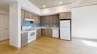 Located at 2045 SW River Parkway in Portland, Oregon, this single-floor unit offers four bedrooms, two bathrooms, and a practical, well-organized layout. The kitchen is a standout feature, outfitted with warm wood-toned cabinetry, light countertops, a blue tile backsplash, hardwood-style flooring, and white appliances including a range, dishwasher, and refrigerator — providing generous storage and functionality. An exposed concrete ceiling in the kitchen and select bedrooms lends an industrial character that contrasts thoughtfully with the clean white walls throughout.

The bedrooms are carpeted and neutral in finish, each offering a calm and versatile space. Several rooms include sliding closet doors, and the unit features a total of four closets for abundant storage. One bedroom benefits from a large window with outdoor views, allowing natural light to fill the room alongside an exposed concrete column that adds architectural interest.

The two bathrooms mirror each other in design, each featuring warm tile flooring, a single vanity with wood cabinetry, a mirror, and a full tub/shower combination with accessibility grab bars. A central hallway connects the rooms efficiently, with light wood-style flooring extending through the common areas. Ceiling fans in several rooms enhance comfort throughout this well-appointed Portland residence.