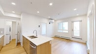 Located at 110 Lucas St NW in Calgary, AB, this well-designed 2-bedroom, 1-bathroom unit offers a clean, modern aesthetic throughout its single-floor layout. Light oak-toned flooring runs continuously across all rooms, complementing the crisp white walls and recessed lighting that keep the space feeling bright and open.

The kitchen is a standout feature, showcasing a contemporary design with a combination of warm wood-toned lower cabinetry and white upper cabinets. A large peninsula with a white quartz countertop and an undermount sink provides ample workspace and casual dining potential. Stainless steel appliances, including a full-size refrigerator and range, complete the functional setup. In-unit laundry is also conveniently accessible nearby.

The spacious primary bedroom offers generous proportions with a large window framing views of the surrounding neighbourhood, along with baseboard heating. The second bedroom is a well-sized, versatile room with direct access to the main living area. A dedicated closet adds practical storage.

The bathroom features a wood-toned vanity with a white countertop, a large mirror, and a full bathtub, all finished in a clean, minimalist style. A private balcony overlooks the developing community, situating this unit within a vibrant and growing area of northwest Calgary.