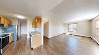 Located at 535 Northland Dr in Saint Joseph, MN, this two-bedroom, one-bathroom single-floor unit offers a well-organized and functional layout. The open-concept living, dining, and kitchen area serves as the heart of the home, featuring warm hardwood-style flooring, vaulted ceilings that lend a sense of spaciousness, and natural light streaming in through large windows. A sliding glass door provides additional light and outdoor access to the living space.

The galley-style kitchen is outfitted with honey-toned wood cabinetry, ample upper and lower storage, a double stainless steel sink, and includes appliances such as a stove, refrigerator, dishwasher, and built-in microwave. Light-toned countertops and textured wallcovering accents complete the kitchen's practical aesthetic.

Both bedrooms are carpeted and feature wood-trimmed windows that bring in views of the surrounding greenery, along with baseboard heating. The generously sized primary bedroom offers comfortable proportions and dedicated closet space. Four closets throughout the unit ensure abundant storage.

The full bathroom includes a wood-vanity with countertop, toilet, and bathtub, finished with hardwood-style flooring. A dedicated laundry area and a central hallway connecting all rooms round out this well-appointed, single-level home.