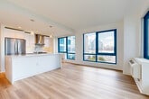 Located at 800 Harbor Blvd in Weehawken, NJ, this well-appointed 3-bedroom, 2-bathroom residence offers a clean, modern aesthetic throughout. Light-toned hardwood flooring runs continuously across the single floor, complementing the bright white walls and recessed lighting that give the space an open, airy feel.

The combined living, dining, and kitchen area serves as the heart of the home, anchored by a large white waterfall-edge island with pendant lighting above. The kitchen features sleek white cabinetry, stainless steel appliances including a refrigerator and range with a wall-mounted hood, and ample counter space. Expansive floor-to-ceiling windows with bold blue frames flood the living area with natural light and frame impressive views of the New York City skyline and Hudson River.

The three bedrooms are generously proportioned, with the spacious primary bedroom offering plenty of room to accommodate a full suite of furnishings. Several bedrooms feature large windows with city and waterway views, and the unit includes an impressive six closets for abundant storage. The two bathrooms are finished with large-format neutral tiles and clean, minimalist fixtures. A dedicated laundry area, entry foyer, and hallway round out this thoughtfully designed residence.