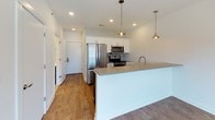 This two-story Deer Valley residence offers a thoughtfully designed 1-bedroom, 1.5-bathroom layout with modern finishes throughout. The kitchen is a standout feature, showcasing white shaker cabinetry, dark lower cabinetry, stainless steel appliances including a refrigerator, microwave, and range, a mosaic tile backsplash, and a spacious island with a light quartz countertop and a deep farmhouse-style sink. Stylish pendant lighting illuminates the space, while warm hardwood-style flooring extends through the main living areas, adding a welcoming feel. The bedroom is generously sized, featuring patterned carpet flooring and a window that frames views of the surrounding neighborhood and cityscape, allowing natural light to fill the room. An en-suite full bathroom is finished with large-format wood-look tile, a soaking tub with tiled surround, a white quartz vanity countertop atop dark cabinetry, brushed nickel fixtures, and a full-width mirror. A convenient half bathroom on the main level is equally well-appointed, featuring a wall-mounted mirror, brushed gold hardware, and a clean white vanity. The home's clean, neutral palette and contemporary finishes create a cohesive and modern living environment throughout.