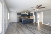 Located at 6407 10th Ave in the Hyde Park neighborhood of Los Angeles, this single-floor, three-bedroom residence offers a thoughtfully designed layout that maximizes every inch of its compact footprint. The space features consistent wood-look plank flooring throughout, lending a cohesive and modern aesthetic from room to room.

The kitchen is a standout feature, showcasing navy blue shaker-style cabinetry with glass-front upper panels, a tile backsplash in neutral tones, stainless steel appliances including a refrigerator and dishwasher, a gas range, and a peninsula with a white marble-style countertop — ideal for casual dining or food prep.

The bedrooms vary in character: the primary bedroom offers a walk-in closet and direct hallway access, while additional bedrooms feature soft blue-grey accent walls, ceiling fans with integrated lighting, and windows fitted with white blinds that allow natural light to filter in. One bedroom provides an outdoor view of surrounding greenery, adding a sense of openness.

A connecting hallway ties the rooms together efficiently. Textured ceilings are consistent throughout the unit. The overall ambiance is clean, modern, and move-in ready, reflecting updated finishes that balance functionality with contemporary style.