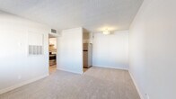 Located at 520 W Prince Rd in Tucson, AZ, this 2-bedroom, 1-bathroom unit offers a practical and well-organized single-floor layout. The living room features neutral wall-to-wall carpeting, a textured ceiling, and an open sightline to the kitchen, creating a connected and airy feel. A partial dividing wall separates the living area from the kitchen nook, where a stainless steel refrigerator is neatly positioned. The kitchen is a standout feature, outfitted with white cabinetry, light quartz-style countertops, a gray subway tile backsplash, a stainless steel double sink, and stainless steel appliances including an electric range and dishwasher, all set over wood-look flooring. Both bedrooms are carpeted and bathed in natural light from windows with horizontal blinds. The primary bedroom offers a comfortable footprint, while the second bedroom includes a built-in closet with rod and shelf storage. Additional closet space is accessible from the hallway. The bathroom features a full tub-shower combination with clean white tile surround and wood-look flooring. Throughout the unit, a consistent neutral palette and textured ceilings contribute to a clean, move-in-ready ambiance.