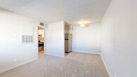 Located at 520 W Prince Rd in Tucson, AZ, this 2-bedroom, 1-bathroom unit offers a practical and well-organized single-floor layout. The living room features neutral wall-to-wall carpeting, a textured ceiling, and an open sightline to the kitchen, creating a connected and airy feel. A partial dividing wall separates the living area from the kitchen nook, where a stainless steel refrigerator is neatly positioned. The kitchen is a standout feature, outfitted with white cabinetry, light quartz-style countertops, a gray subway tile backsplash, a stainless steel double sink, and stainless steel appliances including an electric range and dishwasher, all set over wood-look flooring. Both bedrooms are carpeted and bathed in natural light from windows with horizontal blinds. The primary bedroom offers a comfortable footprint, while the second bedroom includes a built-in closet with rod and shelf storage. Additional closet space is accessible from the hallway. The bathroom features a full tub-shower combination with clean white tile surround and wood-look flooring. Throughout the unit, a consistent neutral palette and textured ceilings contribute to a clean, move-in-ready ambiance.
