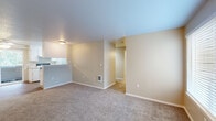 This 2-bedroom, 1-bathroom single-floor residence offers a practical and comfortable layout designed for efficient everyday living. The carpeted living room is bright and welcoming, featuring a large window that fills the space with natural light and provides views of the surrounding neighborhood, along with a ceiling fan for added comfort. A half-wall partition connects the living area to the galley-style kitchen and dining room combination, which features wood-look flooring, white cabinetry lining both walls, light countertops, a stainless steel sink, and white appliances including a range and refrigerator. The primary bedroom is a well-proportioned retreat with plush carpet, a sliding-door closet, a built-in vanity with mirror and sink, and its own access to additional spaces. The second bedroom also features carpet flooring, a window with views of mature trees, and a skylight that brings in additional natural light. The full bathroom is finished in crisp white tones with a tub-shower combination, a granite-topped vanity, and wood-look flooring. A dedicated laundry area and three closets provide ample storage throughout. Neutral wall tones and consistent finishes lend a clean, cohesive aesthetic across the entire residence.