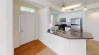 This single-floor residence offers a thoughtfully designed layout that balances comfort and functionality. The entryway welcomes you with warm hardwood flooring and a transom window above the front door, filling the space with natural light. The kitchen is well-equipped with stainless steel appliances, including a refrigerator, electric range, and over-the-range microwave, all complemented by crisp white cabinetry and dark granite-style countertops. A peninsula with a double sink opens directly to the adjacent living and dining area, creating a seamless flow ideal for entertaining. The living area features plush carpeting, a ceiling fan, and windows that invite generous natural light and outdoor views. Multiple bedrooms continue the soft carpet flooring, each fitted with ceiling fans and windows overlooking the surrounding neighborhood. The primary bathroom is elongated, featuring white cabinetry, dark granite-style countertops, a large mirror, tile flooring, and access to a walk-in closet. A tub-shower combination with tiled surround and a separate walk-in closet enhance the primary suite. A second full bathroom mirrors the same clean, functional aesthetic. Throughout, the residence maintains a bright, neutral palette that creates an open and inviting atmosphere.