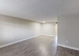 Located at 12 NE 188 St in Miami, FL, this single-floor unit offers a thoughtfully laid-out living space with a clean, modern aesthetic throughout. The open living and dining areas are finished with durable wood-look flooring and neutral gray walls, creating a bright and versatile backdrop. Large sliding glass doors in one of the living areas invite natural light and provide views of lush greenery outside, while additional windows along the front of the unit further enhance the airy atmosphere. The kitchen is well-appointed with crisp white cabinetry, granite-patterned countertops, a stainless steel sink, and matching appliances including a dishwasher and range, offering both style and functionality. The bedroom features the same wood-look flooring and is equipped with dual closets, providing generous storage. Two bathrooms serve the unit: one includes a full soaking tub with tiled surround, while the second features a walk-in tiled shower with mosaic floor tile and chrome fixtures. Textured ceilings are consistent throughout the space, adding subtle architectural character. The overall design is clean and practical, making this Miami residence a comfortable and well-finished space.