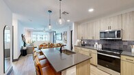 Located at 2500 East Marco Polo Road in Phoenix, AZ, this well-appointed 2-bedroom, 2-bathroom residence offers a thoughtfully designed single-floor layout with a clean, contemporary aesthetic throughout. The open-concept kitchen is a standout feature, boasting light wood cabinetry extending to the ceiling, a textured tile backsplash, stainless steel appliances, and a large center island with a dark quartz countertop and built-in sink — ideal for both cooking and casual dining. Pendant globe lights add an elegant touch above the island, which flows seamlessly into the dining and living areas. The living room is bright and welcoming, with large windows dressed in sheer curtains that invite natural light, a ceiling fan, and a glass-paneled door opening to a private patio. Both bedrooms feature light wood-look flooring, ceiling fans, and ample natural light. Each bedroom is paired with a dedicated closet outfitted with multi-rod shelving systems for generous storage. The two bathrooms reflect the same modern palette, with light wood vanities, dark quartz countertops, glass-enclosed walk-in showers with tile surround, and open wood shelving. The primary bathroom offers an extended layout with direct access to the walk-in closet, enhancing the suite-like feel.