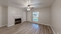 Located at 500 E Loop 820 in Fort Worth, TX, this well-appointed one-bedroom, one-bathroom unit offers a thoughtfully designed single-floor layout with modern updates throughout. The combined kitchen and living area serves as the heart of the home, featuring a tile-surround fireplace with a classic white mantle, a ceiling fan with light fixture, and a window that invites natural light and outdoor views. The kitchen is outfitted with crisp white shaker-style cabinetry, light quartz-style countertops, a light blue subway tile backsplash, and black appliances including an electric range, refrigerator, and dishwasher, all complemented by a stainless steel sink. Wood-look laminate flooring runs consistently throughout the entire unit, adding warmth and cohesion to the space. The bedroom is a comfortable size, benefiting from a ceiling fan, natural light through blinds-covered windows, and access to a dedicated closet. The bathroom is clean and functional, featuring a full tub-shower combo with white tile surround, a grab bar, and a toilet, with a vanity providing additional counter space. A hallway connects the main areas efficiently. The neutral color palette and updated finishes throughout create a bright, move-in-ready atmosphere suitable for a range of lifestyles.