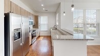 Located at 355 Amistead Ave in Fort Mill, SC, this single-level home offers a clean, modern design with a bright and airy atmosphere throughout. The open-concept living and dining area is anchored by gleaming hardwood-style flooring, large windows dressed with white blinds that invite abundant natural light, and ceiling fans that add both comfort and a classic touch. A chandelier in the dining area adds a refined detail to the shared space.

The kitchen is a standout feature, showcasing granite countertops, warm wood-toned cabinetry, stainless steel appliances including a refrigerator, range, and microwave, and stylish pendant lighting over the breakfast bar. A window above the sink further brightens the workspace.

The bedrooms offer plush carpeting underfoot, ceiling fans, and windows that frame natural views, creating comfortable and restful retreats. The primary bathroom is well-appointed with a double-sink vanity topped in granite, warm wood cabinetry with matte black hardware, dual framed mirrors with industrial-style lighting, and a walk-in shower. A secondary bathroom provides a tub-shower combination with granite countertop vanity. Hardwood-style flooring runs through both bathrooms, tying the home's design together cohesively.