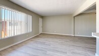 Located at 2433 W Campbell Ave in Phoenix, AZ, this 2-bedroom, 1-bathroom unit is thoughtfully laid out across a single floor. Light wood-look flooring runs throughout the entire space, lending a clean and cohesive aesthetic from room to room. The combined kitchen and living area forms the heart of the home. The kitchen is well-appointed with white cabinetry, marble-style countertops, a double-basin stainless steel sink, and black appliances including a gas range and refrigerator. The living room receives generous natural light through a sliding glass door fitted with vertical blinds, which opens to an outdoor patio area. Both bedrooms are comfortably sized, each featuring sliding double-door closets and windows that invite additional natural light. The spacious primary bedroom offers ample room for furnishings. A connecting hallway provides access to the full bathroom, which includes a vanity with storage, a wall-mounted mirror with overhead lighting, and a tub-shower combination with tiled surround. Neutral warm-beige walls and consistent light flooring throughout the space create a bright, move-in-ready environment well-suited for comfortable everyday living.