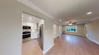 Located at Fairfield Tudor At North Babylon in North Babylon, NY, this single-floor residence combines classic architectural details with contemporary updates throughout. The living areas are defined by light hardwood-style flooring, soft sage-toned walls, and crisp white crown molding that runs consistently through each room, creating a cohesive and polished aesthetic. Ceiling fans with integrated lighting fixtures are installed in the main living spaces, contributing to both comfort and visual continuity.

The kitchen is thoughtfully designed with white shaker-style cabinetry, stainless steel appliances including a range, over-the-range microwave, and refrigerator, as well as a marble-look countertop and coordinating tile backsplash. A stainless steel sink with a brushed gold faucet adds a refined finishing touch. The kitchen connects openly to the main living area, promoting an efficient and functional layout.

The living and sleeping areas are generously proportioned, with recessed lighting and baseboard heating providing year-round comfort. Natural light enters through windows overlooking greenery, enhancing the overall brightness of the space. The bathroom features a soaking tub with a sliding glass enclosure, white subway tile surround, and a frosted privacy window, offering a clean and modern finish throughout.
