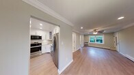 Located at Fairfield Tudor At North Babylon in North Babylon, NY, this single-floor residence combines classic architectural details with contemporary updates throughout. The living areas are defined by light hardwood-style flooring, soft sage-toned walls, and crisp white crown molding that runs consistently through each room, creating a cohesive and polished aesthetic. Ceiling fans with integrated lighting fixtures are installed in the main living spaces, contributing to both comfort and visual continuity.

The kitchen is thoughtfully designed with white shaker-style cabinetry, stainless steel appliances including a range, over-the-range microwave, and refrigerator, as well as a marble-look countertop and coordinating tile backsplash. A stainless steel sink with a brushed gold faucet adds a refined finishing touch. The kitchen connects openly to the main living area, promoting an efficient and functional layout.

The living and sleeping areas are generously proportioned, with recessed lighting and baseboard heating providing year-round comfort. Natural light enters through windows overlooking greenery, enhancing the overall brightness of the space. The bathroom features a soaking tub with a sliding glass enclosure, white subway tile surround, and a frosted privacy window, offering a clean and modern finish throughout.