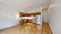 Located at 3627 Stone Way N in Seattle's vibrant Wallingford neighborhood, this efficiently designed unit offers a thoughtful layout that maximizes every square foot. Light hardwood floors run throughout, complementing the clean, modern aesthetic defined by crisp white walls and tall ceilings that lend an airy sense of openness.

The heart of the unit is a combined kitchen, dining, and living area. The kitchen features warm wood cabinetry, white countertops with a tile backsplash, and a full suite of stainless steel appliances including a range, over-the-range microwave, dishwasher, and French door refrigerator. Stylish pendant lights hang above, adding a refined touch. The living area benefits from large sliding glass doors and transom windows that flood the space with natural light and provide direct access to a private patio, where raised planter boxes create an inviting outdoor retreat.

A bright, wide entrance hallway leads into the main living space, maintaining a clean flow throughout. The bathroom is finished with tile flooring and includes a glass-enclosed shower. An in-unit laundry is conveniently combined within the bathroom. A dedicated closet provides practical storage. This well-appointed unit delivers a modern urban lifestyle in one of Seattle's most walkable and sought-after neighborhoods.