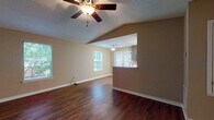 This single-story, one-bedroom, one-bathroom unit offers a well-designed layout that maximizes its comfortable footprint. The living area is a standout space, featuring vaulted ceilings that add a sense of openness and volume, complemented by a ceiling fan with integrated lighting. Rich, dark hardwood-style flooring runs throughout the main living areas, and multiple windows allow abundant natural light to fill the room, offering views of surrounding greenery.

The kitchen is accessible via a pass-through bar that connects it to the living space, facilitating an open feel. It is equipped with stainless steel appliances, including a range, over-the-range microwave, and a French door refrigerator. Dark espresso cabinetry extends to the ceiling for ample storage, and light countertops provide a clean contrast.

The bedroom is generously sized with plush carpeting, a ceiling fan, and a window that brings in natural light. It is accompanied by a walk-in closet featuring wire shelving for organized storage. A dedicated bathroom is conveniently adjacent. The textured ceilings throughout add a consistent finishing detail, contributing to the unit's warm, functional ambiance.