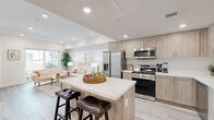 Located at 3050 W 11th St in Los Angeles, CA, this well-appointed 2-bedroom, 2-bathroom residence offers a thoughtfully designed single-floor layout with modern finishes throughout. The open-concept kitchen and living area serves as the heart of the home, where a spacious center island with quartz countertops and bar seating flows seamlessly into the living room. The kitchen is outfitted with a full suite of stainless steel appliances, including a gas range, built-in microwave, dishwasher, and a large French door refrigerator, complemented by light wood cabinetry extending to the ceiling for ample storage. Light wood-style flooring ties the space together. The living room is bright and welcoming, featuring recessed lighting and a sliding glass door that opens to a private outdoor area. Both bedrooms offer a calm, neutral palette with recessed lighting and light-filtering window coverings. The generously sized primary bedroom provides a comfortable retreat. Each bathroom is finished with warm wood vanity cabinetry, quartz countertops, beige tile flooring, and a tub-shower combination enclosed by sliding glass doors. In-unit stacked laundry is also conveniently located within the residence.
