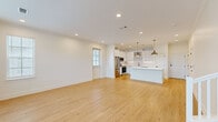 Located in Collierville, Tennessee, this two-story home offers a clean, modern aesthetic throughout its four bedrooms and three bathrooms. The main floor is anchored by a bright, open-concept living area that flows seamlessly into a well-appointed kitchen. The kitchen features white shaker-style cabinetry extending to the ceiling, stainless steel appliances including a refrigerator and range, a white waterfall-edge island, and stylish brass pendant lighting — all set atop light-toned hardwood flooring that runs throughout the home. A convenient half bath on the main level includes a pedestal sink with chrome fixtures. The living room is bathed in natural light from multiple windows dressed with white blinds, lending an airy, welcoming atmosphere. Upstairs, the four bedrooms include a spacious primary suite with a walk-in closet equipped with wire shelving. Additional closets and hallways provide ample storage throughout. A dedicated laundry area with wire shelving and an in-unit washer adds everyday convenience. The attached garage features a clean concrete floor and interior access. Outside, a private gated courtyard area with white fencing completes the home's exterior.