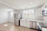Located at 1101 Euclid St NW in Washington, DC's dynamic Columbia Heights neighborhood, this 2-bedroom, 1-bathroom residence offers a thoughtfully designed single-floor layout. Light-toned luxury vinyl plank flooring runs throughout, creating a cohesive and clean aesthetic.

The open-concept kitchen, dining, and living area serves as the heart of the home. The kitchen is outfitted with crisp white shaker cabinetry, light quartz countertops, and a full suite of stainless steel appliances including a refrigerator, dishwasher, electric range, and over-the-range microwave. Multiple windows invite generous natural light into this shared space.

Two bedrooms offer comfortable, well-proportioned retreats with bright white walls and large windows that frame outdoor greenery. The primary bedroom provides a private, sunlit space with access to dedicated closet storage. In total, three closets are distributed throughout the unit, providing ample organization.

The bathroom features a clean, modern finish with white subway tile surrounding the bathtub and shower, complemented by light wood-look flooring and white fixtures. A hallway connects the living spaces to the private quarters, and the entry features a secure door with a keypad lock for added convenience.