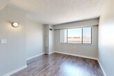 Located at 615 Park St in downtown Des Moines, Iowa, this one-bedroom, one-bathroom unit offers an efficient and well-organized layout across a single floor. The living room is the heart of the unit, featuring rich wood-look hardwood-style flooring, neutral gray walls, a textured ceiling, and a large picture window that fills the space with natural light and frames views of the surrounding cityscape. A wall-mounted sconce adds a functional lighting accent near the entrance.

The kitchen is positioned adjacent to the living area and includes white cabinetry and a dedicated sink, offering a practical cooking space. Three closets throughout the unit provide ample storage, which is a notable feature given the compact footprint.

The bedroom is finished with plush carpeting and benefits from its own large window with city views. A full-length mirrored sliding closet door adds depth and reflects natural light throughout the room. The bathroom is equipped with a full-size bathtub and shower combination, complete with stainless steel grab bars for added safety and accessibility.

Connecting the rooms is a hallway that maintains a clean, neutral aesthetic consistent with the rest of the unit. Overall, the space presents a functional, move-in-ready layout well-suited for urban living in the heart of Des Moines.