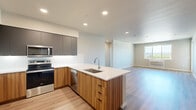 This well-appointed single-floor residence offers three bedrooms, two bathrooms, and a thoughtfully designed layout that maximizes comfort and functionality. The open-concept kitchen and living area serves as the heart of the home, featuring a striking peninsula with warm wood-grain cabinetry, white quartz countertops, and a stainless steel sink. The kitchen is equipped with stainless steel appliances, including a range, microwave, and dishwasher, complemented by sleek grey upper cabinets and recessed lighting overhead. Light hardwood-style flooring flows throughout the main living areas, creating a cohesive and contemporary feel.

The spacious primary bedroom offers generous proportions, with large windows that invite abundant natural light and views of the surrounding landscape, along with direct access to a private balcony. The additional bedrooms feature plush carpeting and wide windows overlooking greenery. The bathrooms are finished with wood-toned vanities, white countertops, and matching hardwood-style flooring for a clean, modern aesthetic.

A dedicated in-unit laundry room houses a full-size front-loading Whirlpool washer and dryer. The home also includes a hallway, entrance area, and a separate living room, rounding out a complete and practical floor plan filled with natural light throughout.