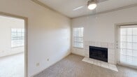 This well-appointed two-bedroom, two-bathroom residence at 165 Forestbrook Dr in Lewisville, TX offers a thoughtfully designed single-level layout. The kitchen is a functional highlight, featuring granite countertops, gray cabinetry, wood-look flooring, a peninsula with a sink, and black appliances including a refrigerator, electric range, and built-in microwave. The kitchen flows naturally toward the living room, which is anchored by a tile-surround fireplace and ceiling fan, with a window that allows natural light to filter in through white blinds. Both bedrooms are carpeted and bright, each featuring windows with views of surrounding greenery. The primary bedroom offers a generous footprint with a dedicated closet featuring built-in shelving and hanging rods. The two bathrooms mirror each other in finish quality, each offering granite vanity countertops, gray cabinetry, framed mirrors, and a tub-shower combination with white tile surround and wood-look flooring. Additional conveniences include an in-unit laundry area and a dedicated closet for storage. The neutral color palette and consistent finishes throughout create a clean, cohesive aesthetic well-suited for comfortable everyday living.