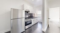 Located at 744 Beacon Avenue in Los Angeles, CA, this one-bedroom, one-bathroom unit offers a thoughtfully designed single-floor layout. The space is finished with dark hardwood flooring throughout, creating a sleek and cohesive aesthetic against the crisp white walls and trim.

The kitchen is a standout feature, showcasing white shaker-style cabinetry, dark granite countertops, and a classic gray subway tile backsplash. Stainless steel appliances — including a full-size refrigerator and a gas range — complete the modern, functional setup. A window above the sink brings in natural light, enhancing the clean, bright feel of the space.

The generously sized bedroom offers ample room for furnishings, with a large window fitted with blinds that frame views of the surrounding neighborhood. A wall-mounted heater unit provides in-room climate control, and a paneled closet door adds a classic architectural touch.

The bathroom is clean and straightforward, featuring a full-size soaking tub with a combination shower, finished in crisp white surroundings with chrome fixtures. An additional room provides flexible space that could serve as a living area or home office, also benefiting from natural light through a sizable window. Overall, the unit presents a clean, move-in-ready environment in a central Los Angeles location.