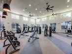 This state-of-the-art fitness center, located in Austin, TX, spans 1,610 square feet on a single floor. The space is characterized by its modern design and thoughtful layout. Wood-paneled walls add warmth and texture, contrasting beautifully with the sleek exercise equipment.

The main workout area boasts high ceilings with multiple ceiling fans, ensuring proper air circulation. Large windows line the walls, flooding the space with natural light and offering views of the surroundings. The flooring alternates between carpeted and hardwood areas, defining different workout zones.

A diverse range of fitness equipment is available, including cardio machines, weight training apparatus, and functional training tools. The center features both open spaces and glass-enclosed rooms, allowing for various types of workouts and classes.

Lighting is well-considered, with a combination of recessed ceiling lights and pendant lamps. The overall ambiance is clean, spacious, and inviting, encouraging members to pursue their fitness goals in a comfortable, well-equipped environment.