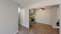 This single-floor, 2-bedroom, 1-bathroom unit is thoughtfully designed to maximize functionality and comfort. The living area features durable wood-look flooring, neutral gray walls, a textured ceiling, and a wall-mounted A/C unit, with a window allowing natural light to brighten the space. The layout flows naturally from the living area into the kitchen, which is equipped with gray cabinetry, granite-look countertops, a black refrigerator, and a ceiling fan overhead — lending a practical yet modern feel to the dining and cooking space. Both bedrooms are finished with plush carpet flooring, neutral gray walls, and textured ceilings. The first bedroom includes a closet with built-in shelving, while the second bedroom offers ample storage with two separate closets, one of which is a walk-in style. The full bathroom features wood-look flooring, a gray vanity with a granite-look countertop, a large mirror with overhead lighting, and a shower-tub combination with a sliding glass door. Clean white trim and consistent neutral tones throughout the unit create a cohesive, move-in-ready atmosphere suited for comfortable everyday living.