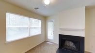 This single-floor, one-bedroom, one-bathroom residence offers a thoughtfully arranged layout that makes efficient use of its space. The living area serves as the heart of the home, characterized by neutral, light-toned walls and soft carpeted flooring that contribute to a warm and inviting ambiance. A classic wood-burning fireplace with a clean white mantel and dark surround serves as a standout focal point in the living room, adding both charm and functionality. Natural light flows generously through large windows dressed with horizontal blinds, creating a bright and airy atmosphere throughout the day. A private exterior door in the living area provides direct outdoor access, enhancing convenience and connectivity to the outside. The textured ceiling adds a subtle architectural detail consistent throughout the space. The home's straightforward single-floor design ensures easy accessibility and flow between rooms. Overall, this residence presents a comfortable and functional living environment, ideal for those seeking a cozy, low-maintenance space with key features such as a fireplace and ample natural light.