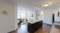 This well-appointed single-floor unit offers a thoughtfully designed open-concept layout that seamlessly connects the kitchen, dining, and living areas. The kitchen is a standout feature, outfitted with dark cabinetry contrasted by bright white upper cabinets, granite countertops, a central island, and a full suite of stainless steel appliances including a refrigerator, electric range, microwave, and dishwasher. Track lighting overhead adds a modern touch throughout the main living space.

The living area is bright and welcoming, anchored by large floor-to-ceiling windows that allow generous natural light and outdoor views. Rich hardwood-style flooring runs throughout the main living areas, adding warmth and continuity to the space.

The unit includes multiple bedrooms, each carpeted and fitted with windows offering natural light and outdoor scenery. The bedrooms provide comfortable, functional spaces suitable for rest or work.

Two bathrooms serve the unit, each featuring granite-topped vanities and dark tile flooring. One bathroom includes a shower-tub combination, while the other offers a standalone shower, both finished with consistent, clean detailing.

Overall, the unit presents a contemporary aesthetic with practical finishes, an efficient use of space, and a bright, open atmosphere throughout.