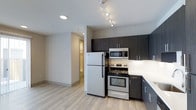 Located at 1516 Xavier Street in Denver's vibrant 80204 corridor, this single-floor residence offers a clean, modern aesthetic throughout. The kitchen is a standout feature, appointed with stainless steel appliances including a full-size refrigerator, electric range, and built-in microwave. Dark espresso-toned cabinetry extends from counter height to the ceiling, providing generous storage while creating a striking visual contrast against the white countertops and light-toned walls. Track lighting overhead ensures the kitchen is well-illuminated, adding both functionality and a contemporary flair. The light wood-style flooring runs seamlessly through the space, lending warmth and continuity to the open layout. A hallway visible from the kitchen connects the living area to additional spaces within the unit, suggesting a thoughtful, efficient floor plan. The overall design balances modern finishes with practical functionality, making this Denver property a well-appointed space suited for everyday living. Its location in the 80204 zip code places it within close proximity to Denver's cultural amenities, dining, and transit options.