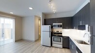 Located at 1516 Xavier Street in Denver's vibrant 80204 corridor, this single-floor residence offers a clean, modern aesthetic throughout. The kitchen is a standout feature, appointed with stainless steel appliances including a full-size refrigerator, electric range, and built-in microwave. Dark espresso-toned cabinetry extends from counter height to the ceiling, providing generous storage while creating a striking visual contrast against the white countertops and light-toned walls. Track lighting overhead ensures the kitchen is well-illuminated, adding both functionality and a contemporary flair. The light wood-style flooring runs seamlessly through the space, lending warmth and continuity to the open layout. A hallway visible from the kitchen connects the living area to additional spaces within the unit, suggesting a thoughtful, efficient floor plan. The overall design balances modern finishes with practical functionality, making this Denver property a well-appointed space suited for everyday living. Its location in the 80204 zip code places it within close proximity to Denver's cultural amenities, dining, and transit options.