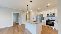 Located at 275 New Towne Dr in Bowling Green, KY, this well-designed one-bedroom, one-bathroom unit offers a thoughtful layout across a single floor. The open-concept kitchen and living area serves as the heart of the home, anchored by a large central island with granite countertops, an undermount sink, and pendant lighting overhead. White shaker-style cabinetry lines the kitchen walls, complemented by a classic subway tile backsplash and a full suite of stainless steel appliances, including a refrigerator, range, microwave, and dishwasher. Warm hardwood-style flooring flows consistently throughout the entire unit, lending a cohesive and modern aesthetic. The spacious living room features crown molding, a ceiling fan, and double French doors that invite natural light and provide outdoor access. The bedroom is a comfortable retreat with its own ceiling fan, a window with outdoor views, and easy access to a dedicated closet. The bathroom includes a bathtub with shower, toilet, and clean neutral finishes consistent with the rest of the unit. Soft sage-green walls throughout create a calm, welcoming ambiance, making this a practical and attractive space in a convenient Bowling Green location.