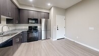 Located at 9410 E Ray Rd in Mesa, AZ, this single-floor, one-bedroom, one-bathroom residence offers a thoughtfully designed layout with modern finishes throughout. Light-toned wood-style flooring flows seamlessly across all rooms, complementing the warm neutral wall tones that give the space a clean, contemporary feel.

The kitchen serves as a functional centerpiece, featuring dark espresso-toned cabinetry that extends to the ceiling for ample storage, granite-look countertops, and a full suite of black appliances including a range, microwave, and dishwasher, alongside a stainless steel refrigerator. A large-format tile floor anchors the kitchen area, which opens naturally into the main living space.

The living area benefits from an open layout with clear sightlines to the kitchen, creating a connected and versatile space. The bedroom is a comfortable, well-proportioned room with two windows dressed in roller shades that allow natural light while maintaining privacy, along with views of the surrounding Mesa landscape.

The bathroom is well-appointed with a dark vanity cabinet, granite countertop, a full tub-shower combination with a curved rod, and consistent wood-style flooring. Clean white paneled doors and crisp white trim throughout the unit add a polished, modern touch to every room.