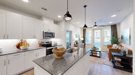 Located at 4600 East McKinney Street in Denton, TX, this thoughtfully designed 2-bedroom, 2-bathroom residence offers a clean, modern aesthetic across a single-level floor plan. The open-concept kitchen and living area serves as the heart of the home, anchored by a granite-topped island with an undermount sink and stylish pendant lighting. White shaker cabinetry, a subway tile backsplash, and stainless steel appliances — including a range, microwave, and refrigerator — complete the well-appointed kitchen. Light wood-tone flooring flows throughout the main living areas, complementing the bright, neutral palette. The living room features a ceiling fan and large windows with a glass door that invite abundant natural light and outdoor views. Each bedroom is carpeted and generously sized, with large windows providing ample daylight. The primary bedroom connects to a private en-suite bathroom featuring granite countertops, white cabinetry, and a walk-in closet with built-in shelving. The second bathroom mirrors the same refined finishes. Two dedicated closets offer excellent storage throughout. The overall ambiance is contemporary and welcoming, with cohesive finishes that create a polished, move-in-ready living environment.