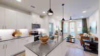 Located at 4600 East McKinney Street in Denton, TX, this thoughtfully designed 2-bedroom, 2-bathroom residence offers a clean, modern aesthetic across a single-level floor plan. The open-concept kitchen and living area serves as the heart of the home, anchored by a granite-topped island with an undermount sink and stylish pendant lighting. White shaker cabinetry, a subway tile backsplash, and stainless steel appliances — including a range, microwave, and refrigerator — complete the well-appointed kitchen. Light wood-tone flooring flows throughout the main living areas, complementing the bright, neutral palette. The living room features a ceiling fan and large windows with a glass door that invite abundant natural light and outdoor views. Each bedroom is carpeted and generously sized, with large windows providing ample daylight. The primary bedroom connects to a private en-suite bathroom featuring granite countertops, white cabinetry, and a walk-in closet with built-in shelving. The second bathroom mirrors the same refined finishes. Two dedicated closets offer excellent storage throughout. The overall ambiance is contemporary and welcoming, with cohesive finishes that create a polished, move-in-ready living environment.