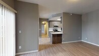 This single-floor unit presents a cohesive, modern design highlighted by a neutral gray and warm wood color palette carried throughout the space. The open-concept living and dining area features light-toned laminate flooring and flows seamlessly into the kitchen via a peninsula with a dark wood-grain finish, providing both a visual anchor and a functional divider between spaces.

The galley-style kitchen is well-appointed, featuring wood-toned cabinetry on both sides, white quartz-style countertops, a classic subway tile backsplash, and a full suite of stainless steel appliances including a range, microwave, refrigerator, and dishwasher. A ceiling-mounted light fixture provides focused illumination over the workspace.

The bedrooms offer a comfortable retreat, each with plush carpeting, gray-toned walls, and windows dressed with vertical blinds that allow natural light while maintaining privacy. Closet access is included in each room.

Two full bathrooms maintain a clean, functional aesthetic, each equipped with a tub-shower combination, light laminate flooring, wood-toned vanity cabinetry, and white countertops. A hallway with an arched architectural detail connects the main living areas to the private rooms, adding a subtle design element to the overall layout.
